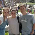 Threefriendssmilingtogetheroutsideoncampus