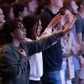 Studentsraisinghandsinworshipduringchapel